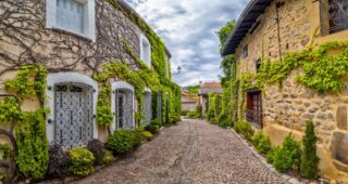A,Narrow,Street,Lined,With,Stone,Buildings,Covered,In,Lush