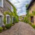 A,Narrow,Street,Lined,With,Stone,Buildings,Covered,In,Lush