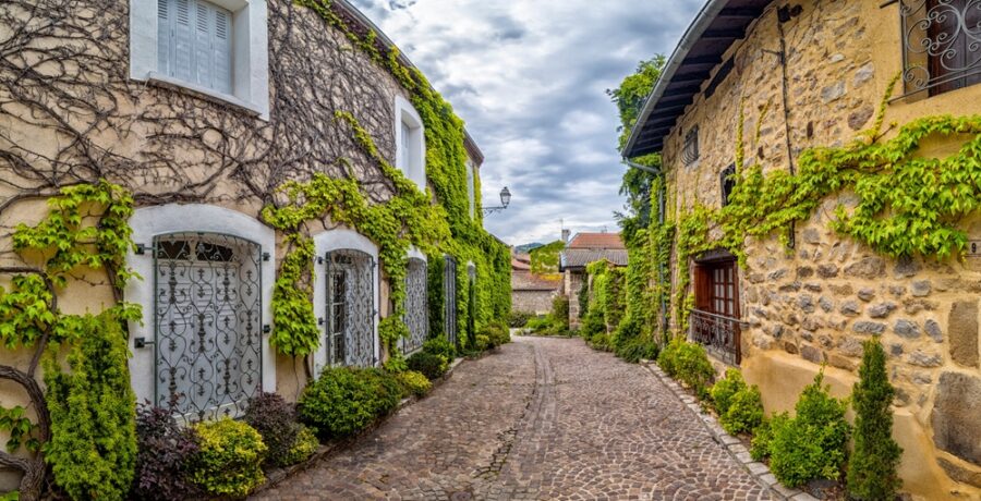 A,Narrow,Street,Lined,With,Stone,Buildings,Covered,In,Lush